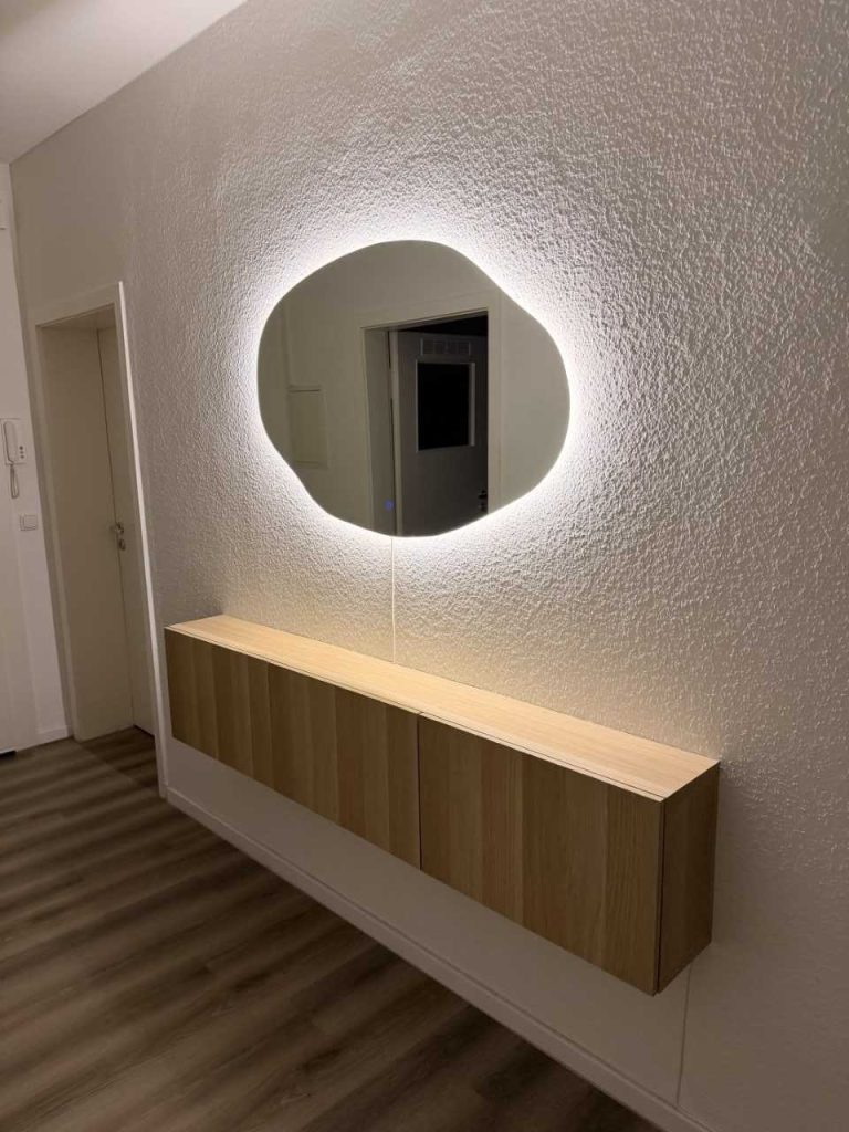 Unregelmäßiger LED-Spiegel Mirage mit Hinterleuchtung im Flur über einer hängenden Eichenkommode